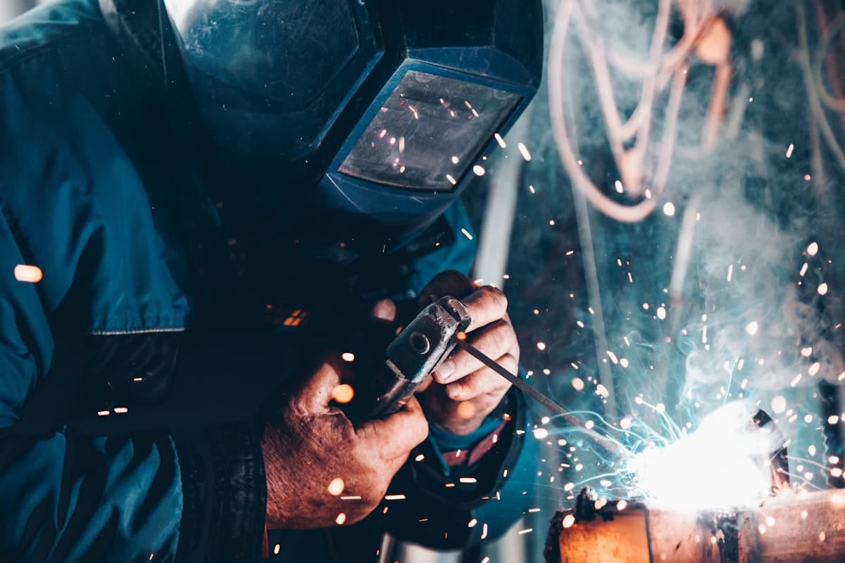 Welder working on metal pipe in an industrial workspace
